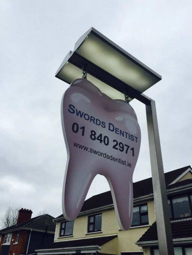 a sign for a dental practice in front of a row of houses