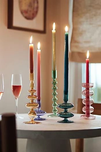 a table topped with lots of candles and wine glasses next to each other on top of a white table