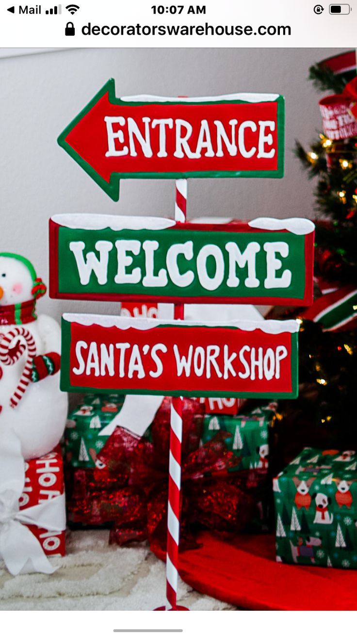 a snowman is standing next to a sign that says entrance welcome santa's workshop