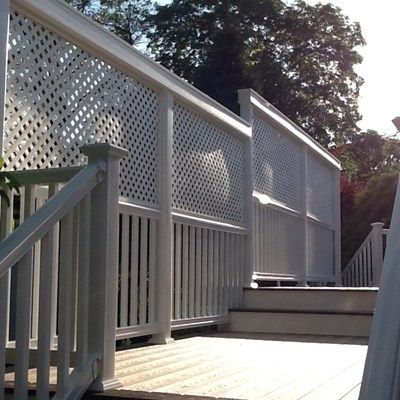 a white deck with railing and steps leading up to trees