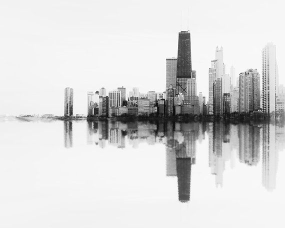 a black and white photo of a cityscape with buildings in the background that is reflected in water