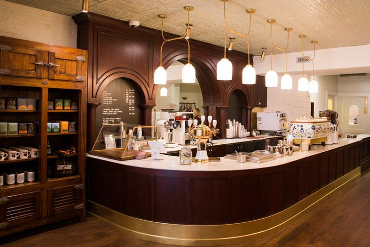 the interior of a coffee shop with lots of counter space and lights hanging from the ceiling