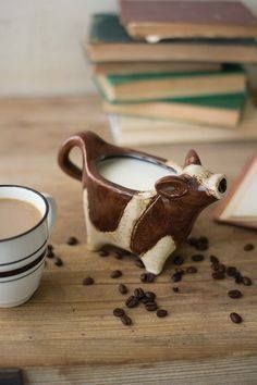 a coffee cup sitting on top of a wooden table next to a cow figurine