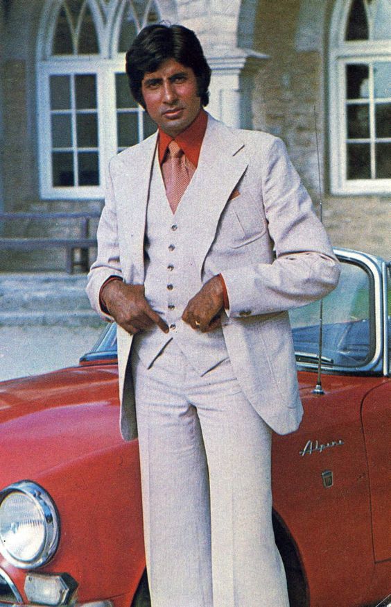 a man in a suit standing next to a red car