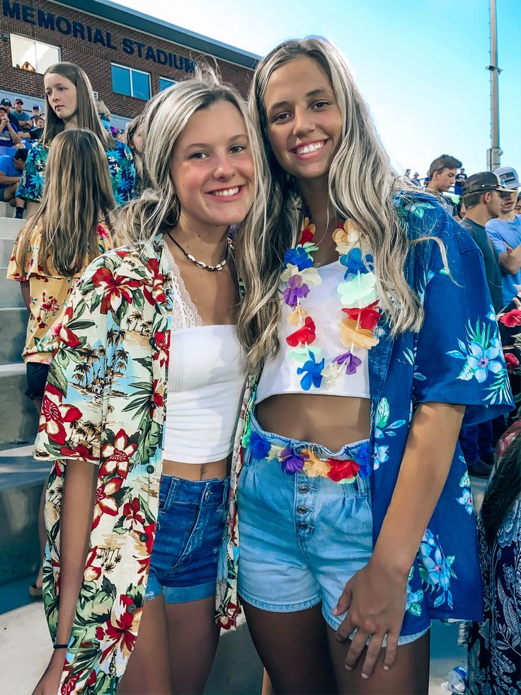 two women standing next to each other in front of a crowd at a football game