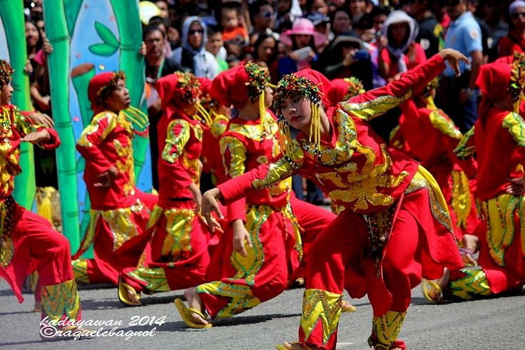 a group of people in red and yellow outfits dance on the street while others watch