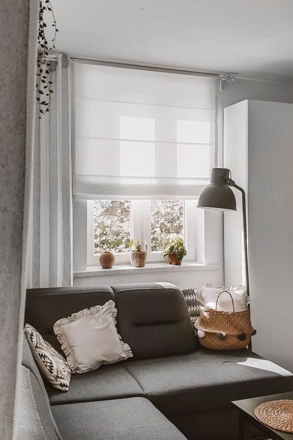 a living room with a gray couch and white curtains in front of a large window