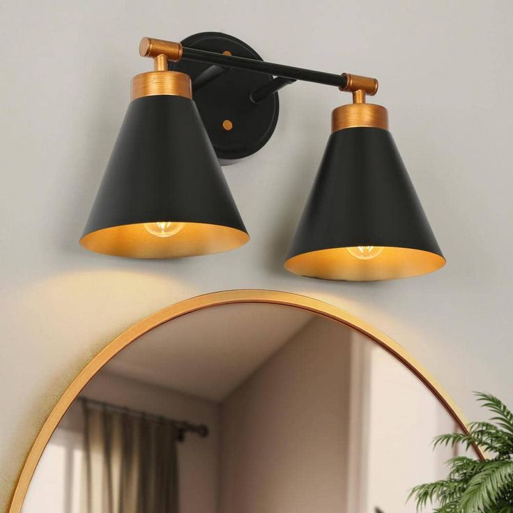 two black and gold lights on a wall above a mirror