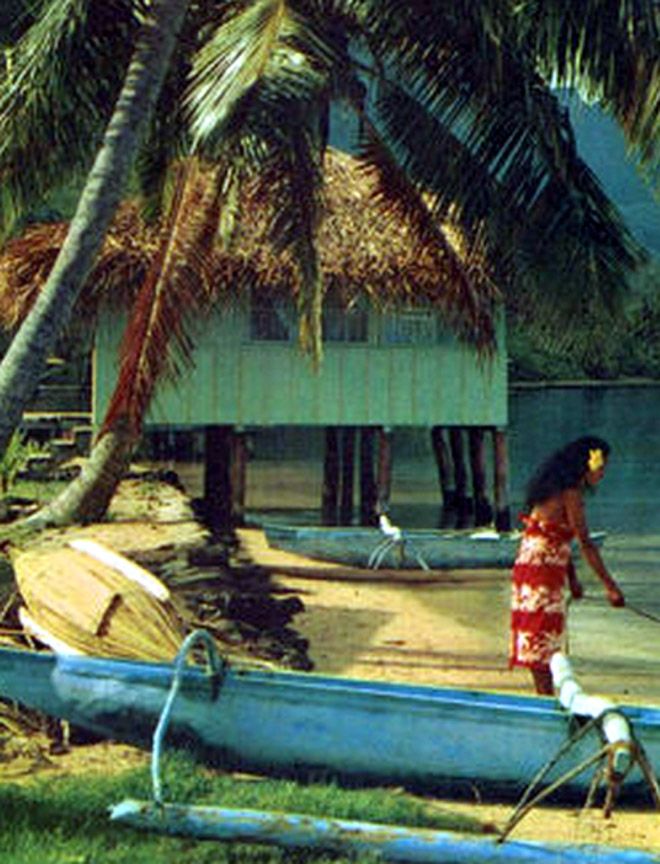 a woman walking on the beach next to a boat