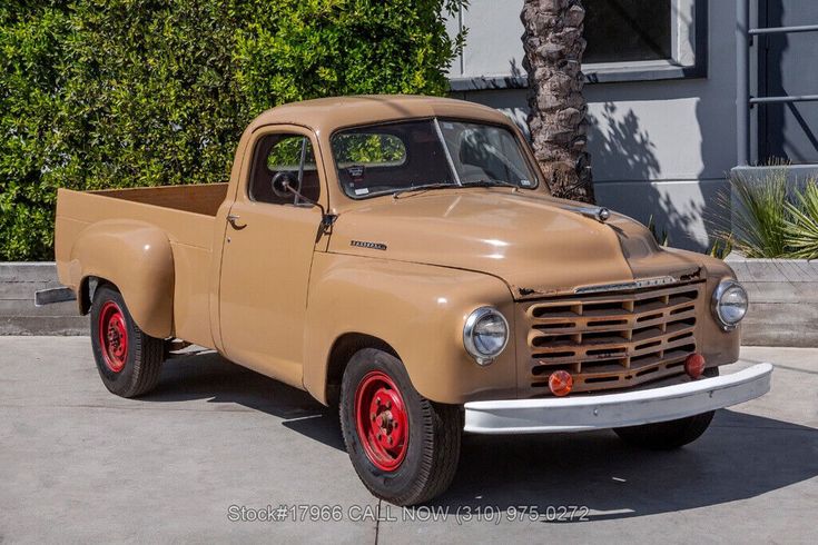 an old tan truck parked in front of a house next to a tall palm tree