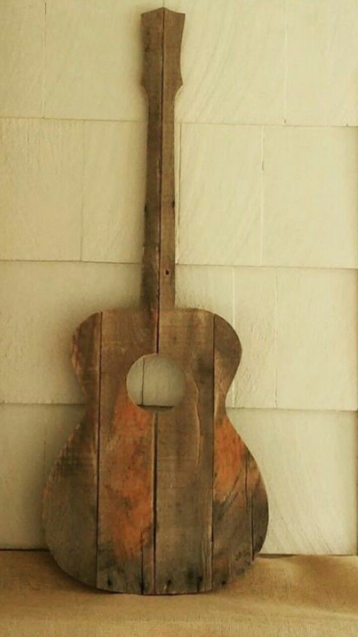 an old wooden guitar sitting on top of a shelf next to a brick wall with white paint