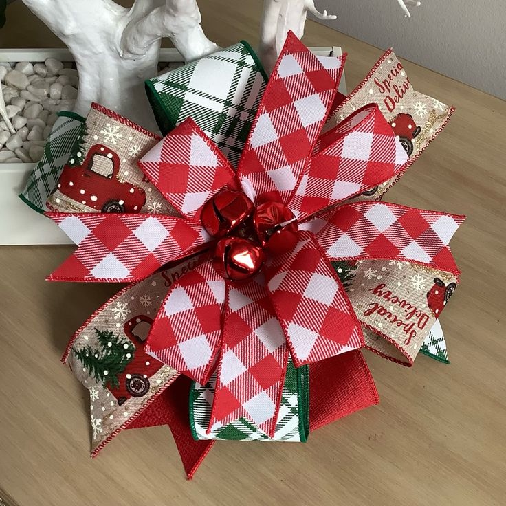 a red, white and green christmas bow on a table next to other holiday decorations