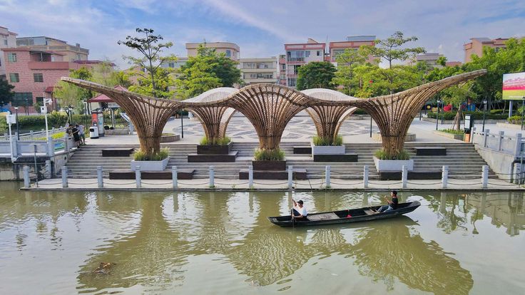 a small boat floating on top of a river next to a park filled with benches