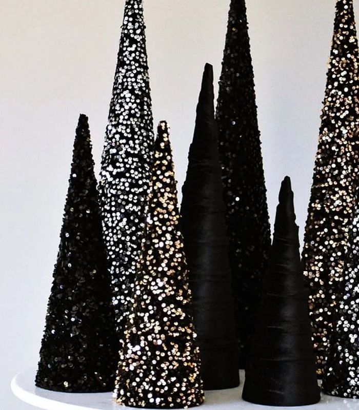 black and white christmas trees are on a cake plate with gold sprinkles