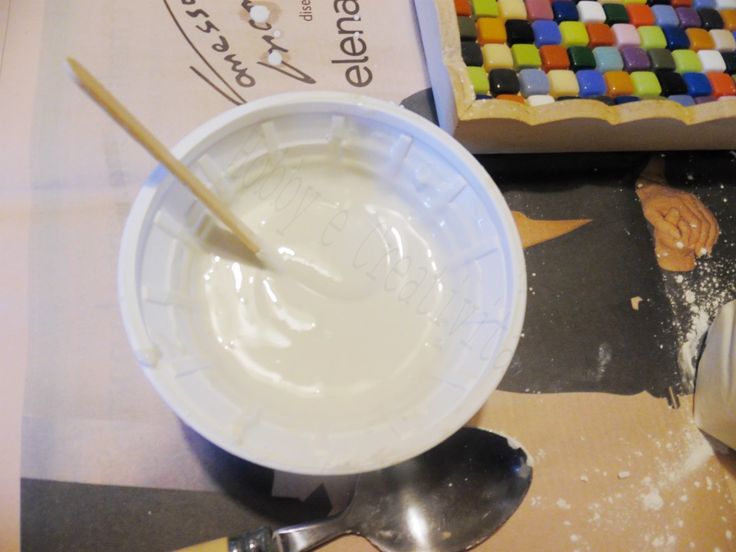 a white bowl filled with liquid next to a wooden spoon on top of a table