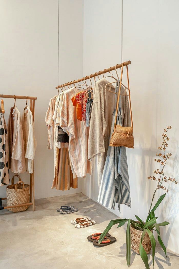 clothes hanging in a room with shoes and sandals on the floor next to each other