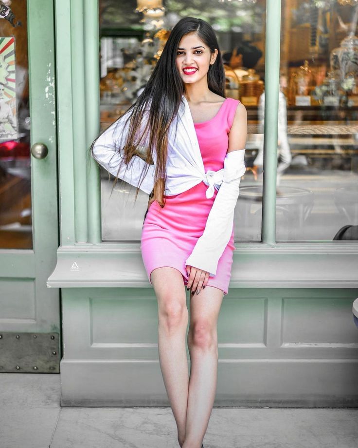 a woman in a pink dress and white jacket leaning on a window sill