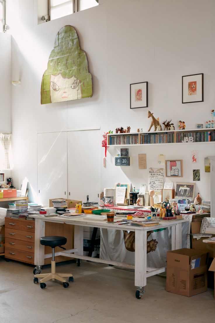 an office with lots of clutter on the desk and shelves in front of it