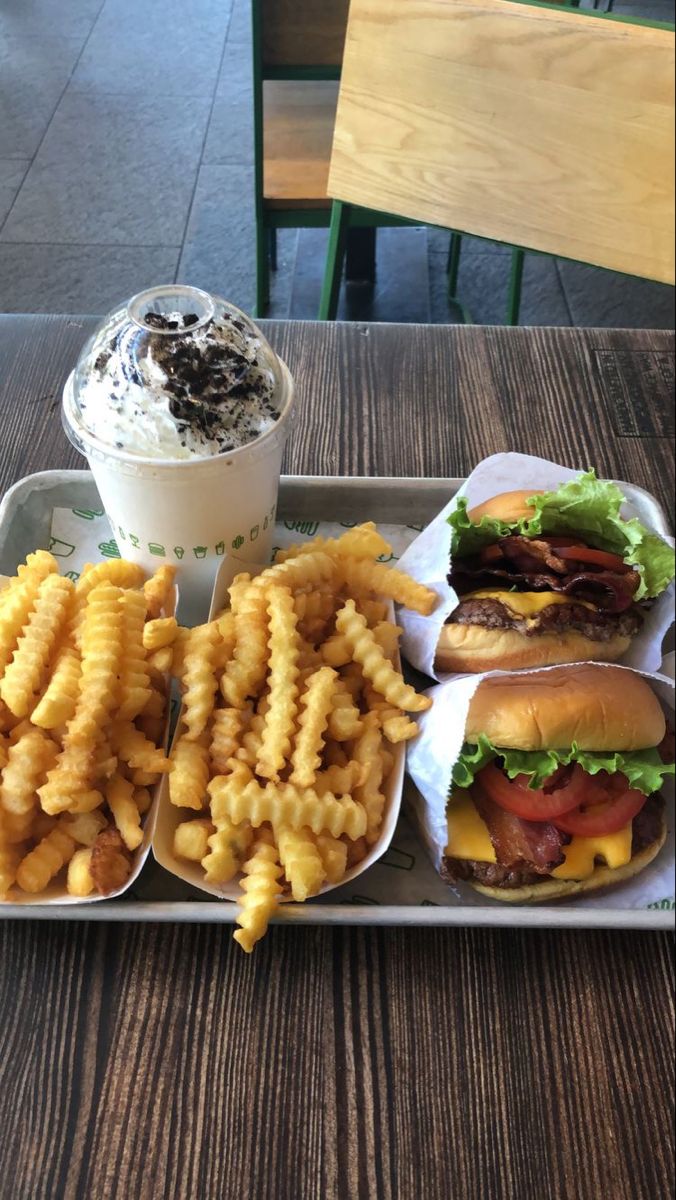 a tray with fries, hamburgers and other food on it sitting on a table