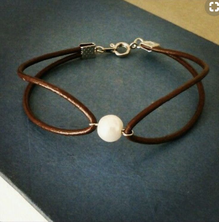 a brown leather bracelet with a white pearl