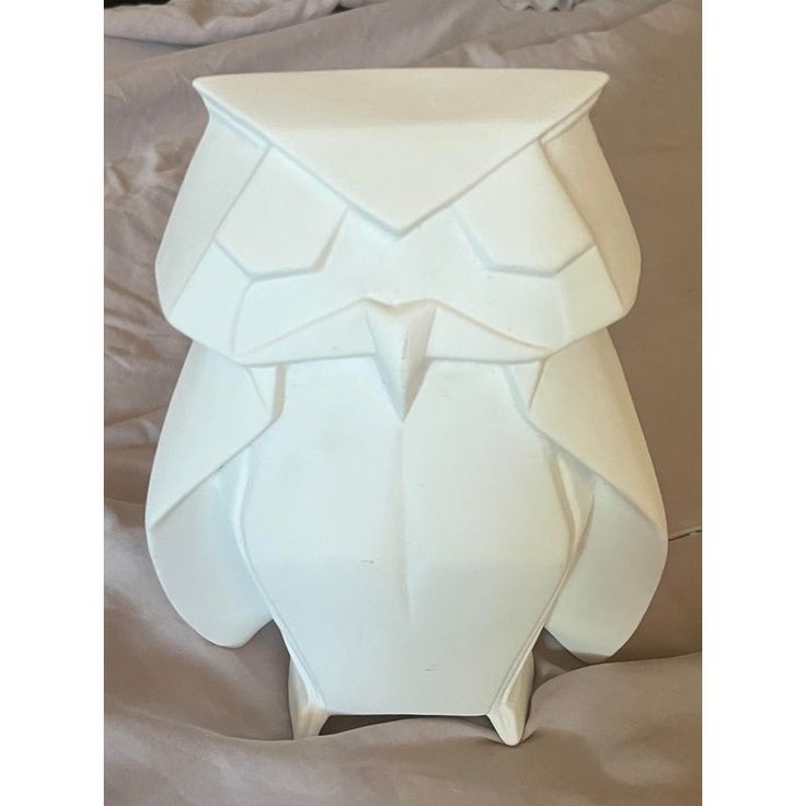 an owl shaped vase sitting on top of a bed