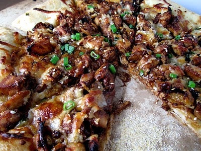 a pizza with meat and green onions on it is cut into four pieces to be eaten