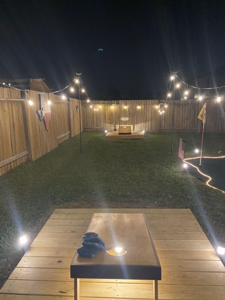 an outdoor patio with lights on it and a coffee table in the foreground at night