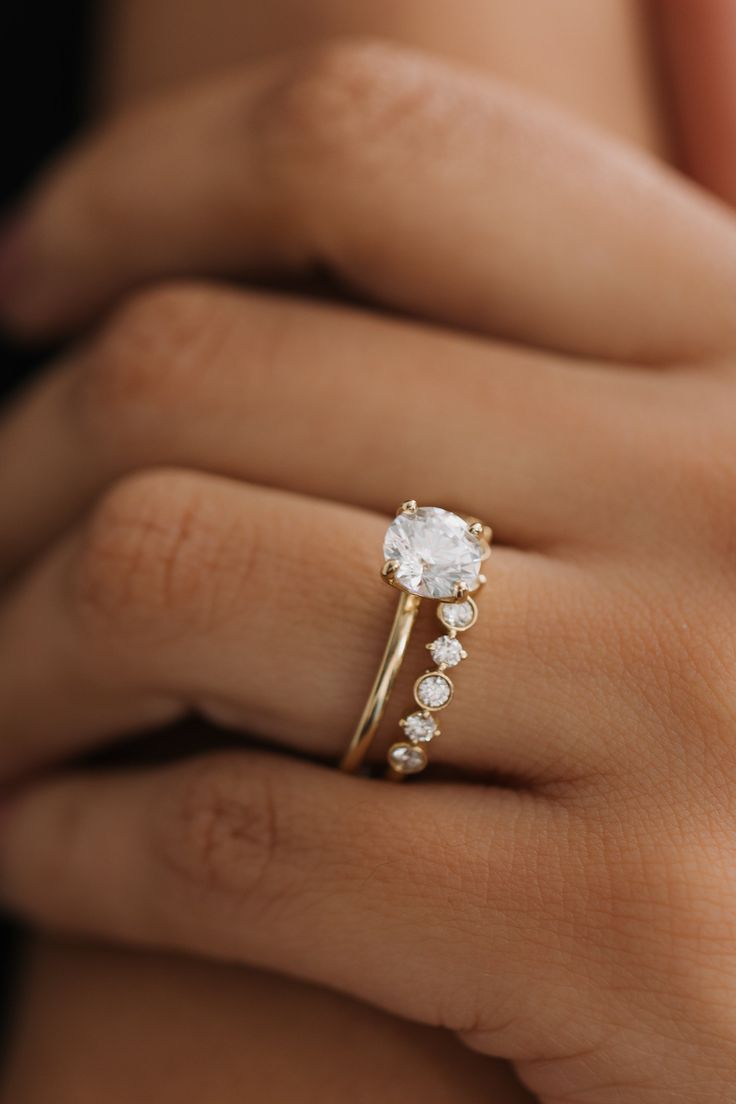 a woman's hand with a diamond ring on top of her finger and an engagement band