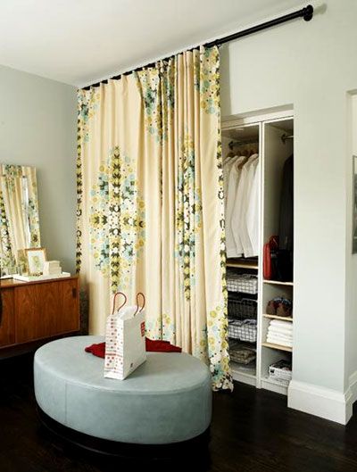 a living room filled with furniture and a large window covered in floral drapes next to a dresser