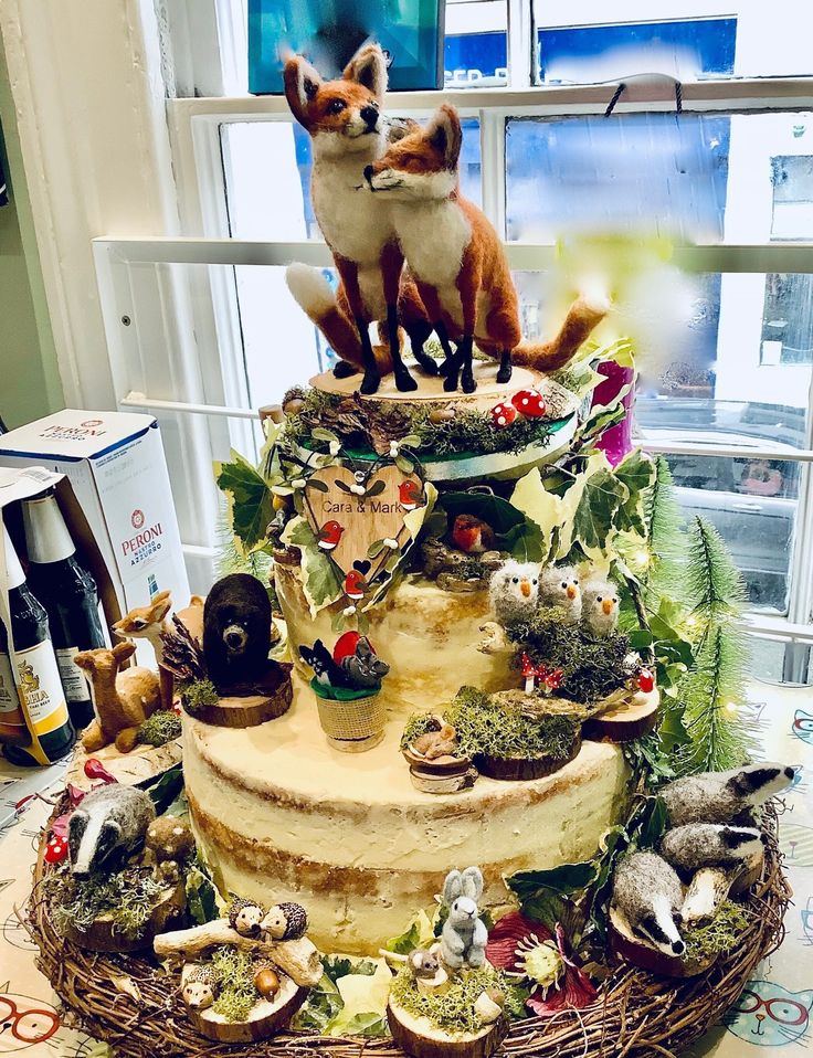 a three tiered cake decorated with figurines of foxes and other animal figures