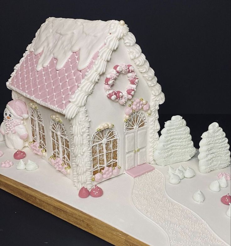 a white and pink gingerbread house on a table