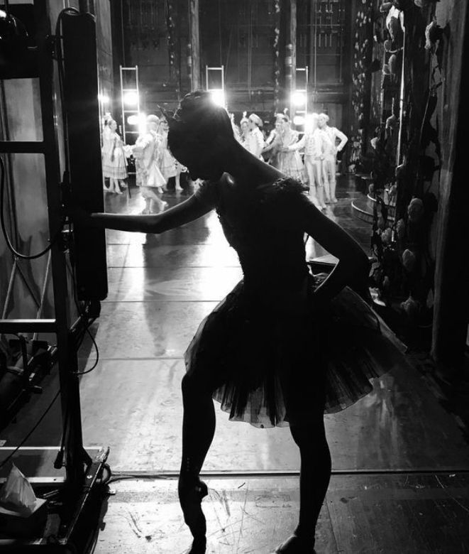 a ballerina is standing in the middle of a dance studio