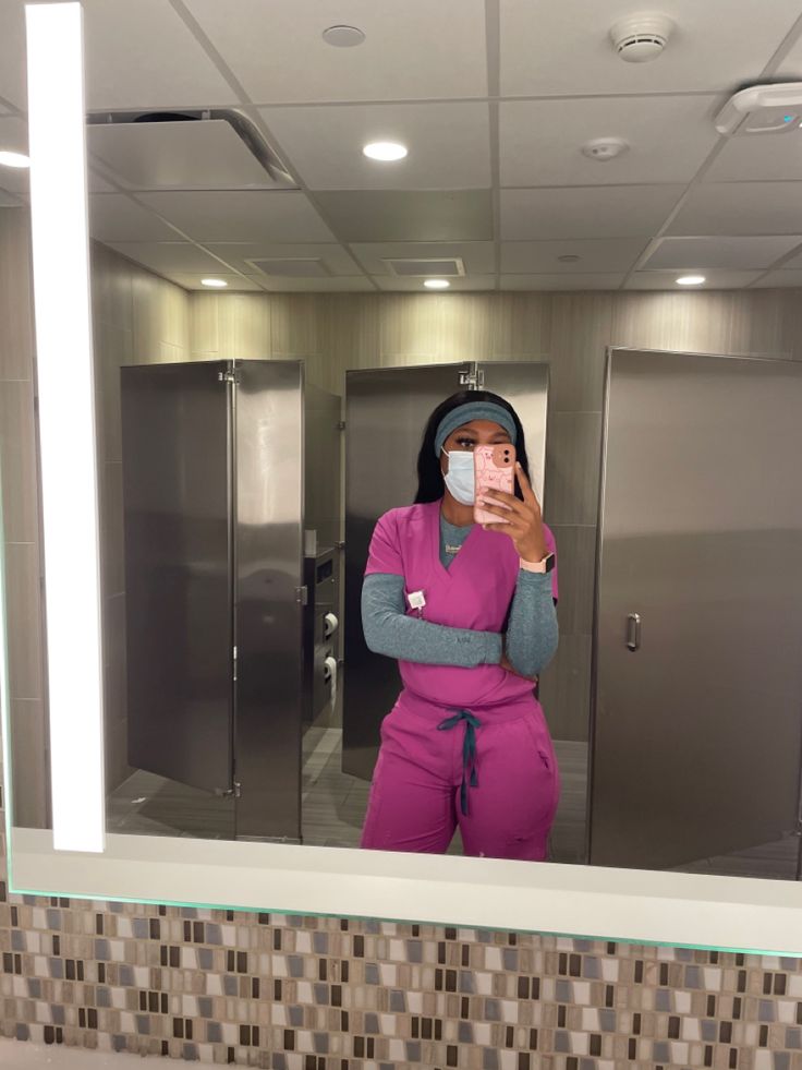 a woman in pink is taking a selfie in the bathroom mirror with her cell phone