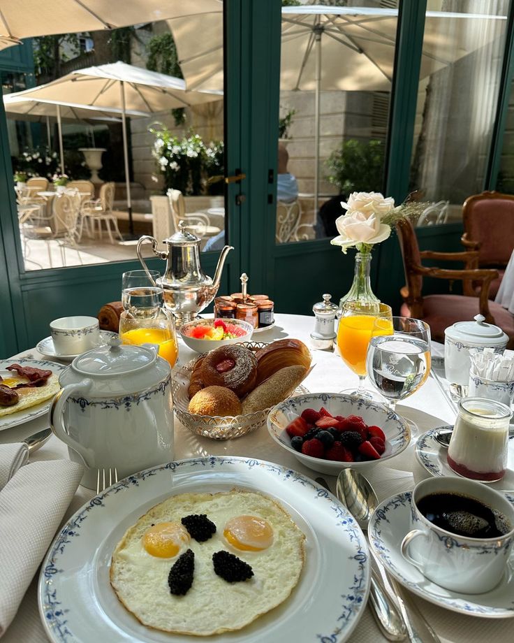 a table topped with breakfast foods and glasses of orange juice on top of a white table cloth