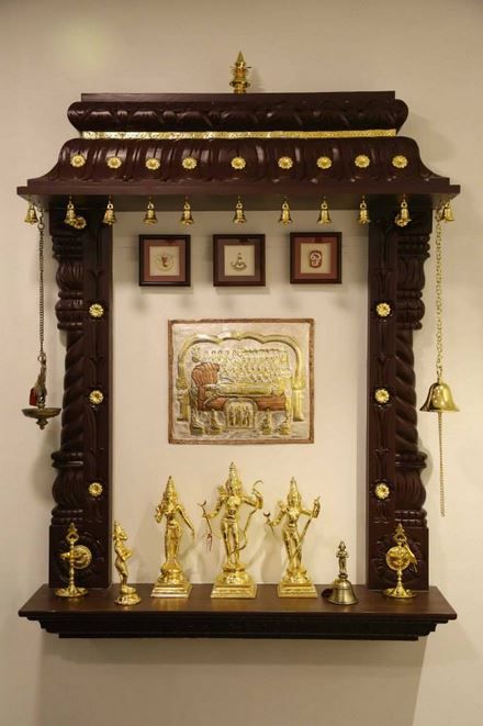 an ornate wooden shelf with gold decorations and pictures on the wall in front of it