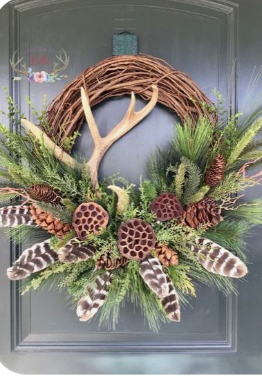 a wreath with antlers and pine cones hanging on a door