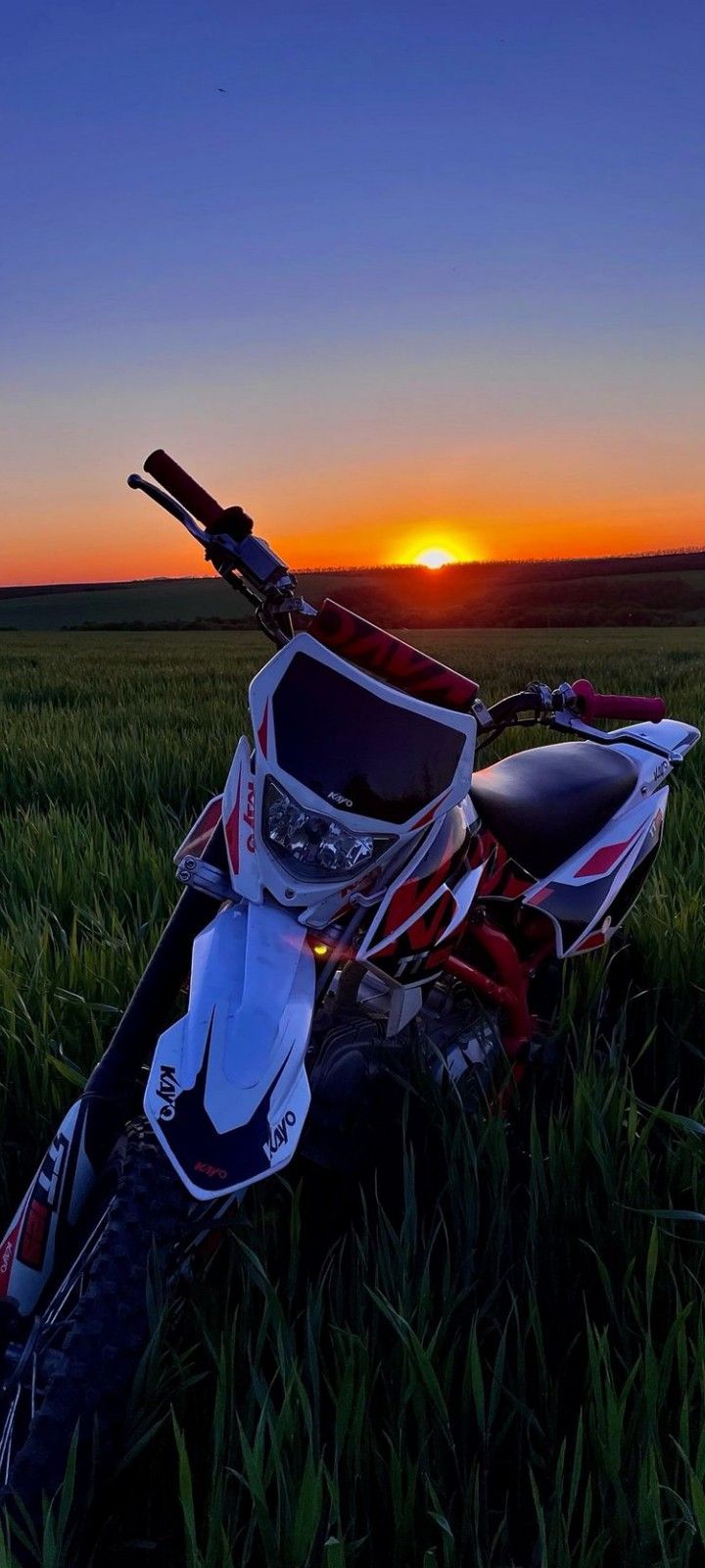 a dirt bike sitting in the grass at sunset