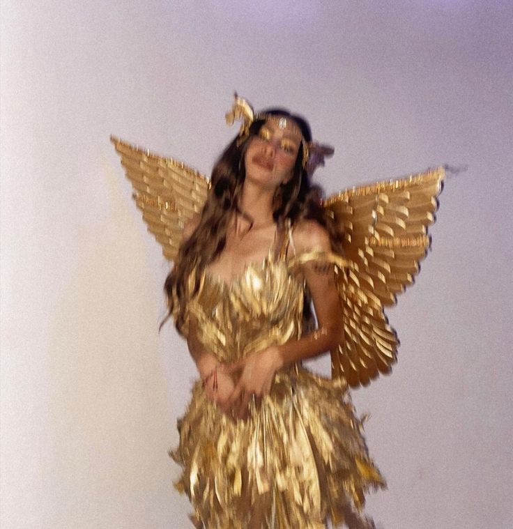 a woman dressed in gold is posing for the camera