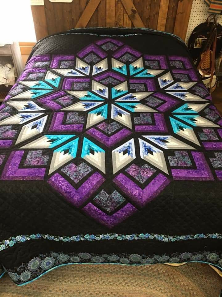 a bed with a purple and blue quilt on it