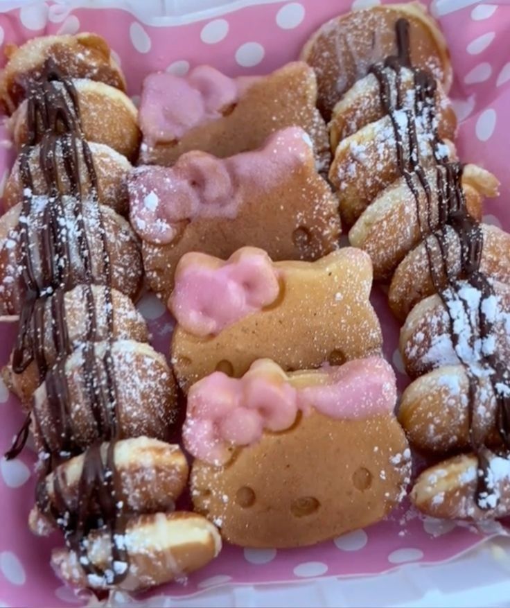 hello kitty donuts are arranged in a pink polka dot tray with chocolate drizzled on them