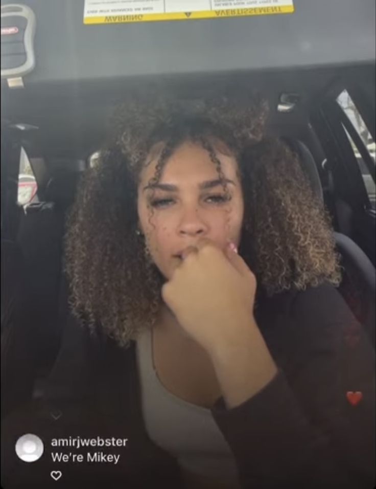 a woman sitting in the back seat of a car with her hand on her mouth