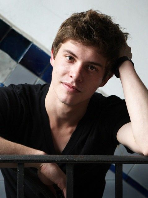 a young man leaning on a railing with his hands behind his head