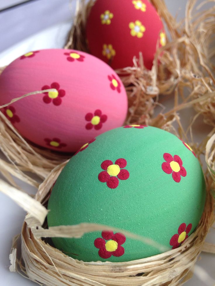 three decorated eggs sitting in a nest on a table