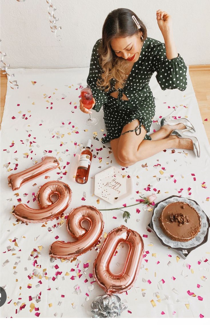 a woman sitting on the floor with balloons and confetti in front of her