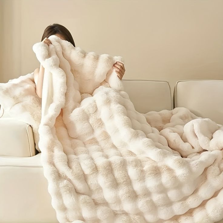 a woman wrapped up in a fluffy white blanket