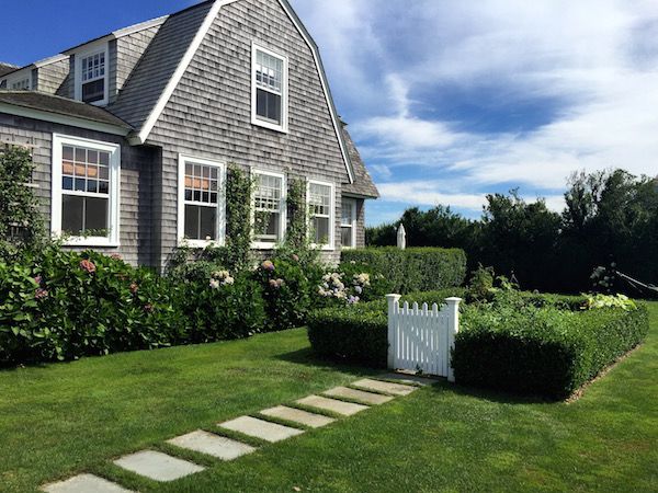 a house with a white picket fence in front of it and green grass on the side