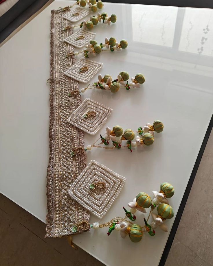 several pieces of bead work on a white table with flowers in the middle and beads hanging from it