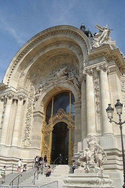 the entrance to an ornate building with statues on it