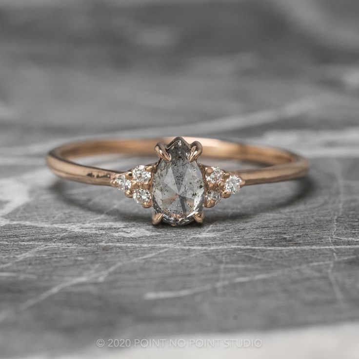 an engagement ring with three stones on top and two diamonds in the middle, sitting on a stone surface