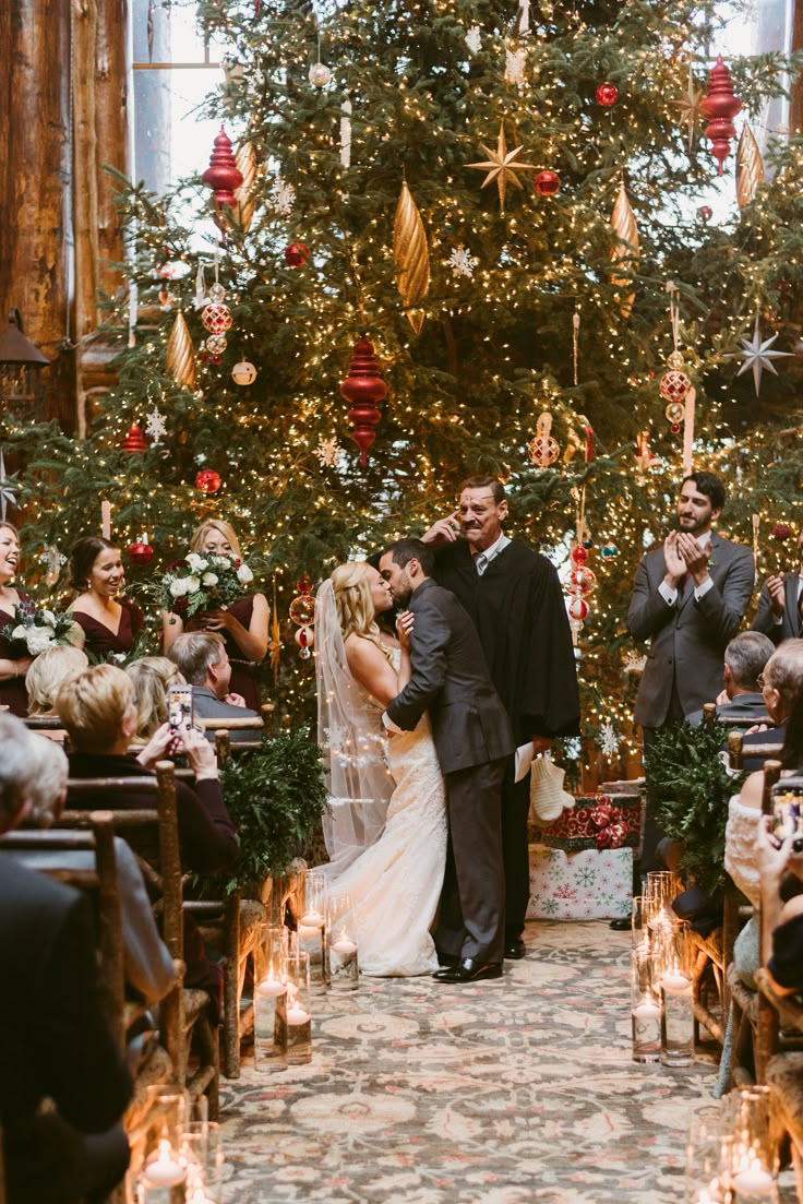 a bride and groom standing in front of a christmas tree at the end of their wedding ceremony